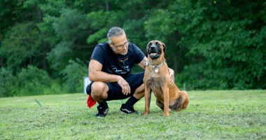 Rescue dog sitting in a field with his new owner